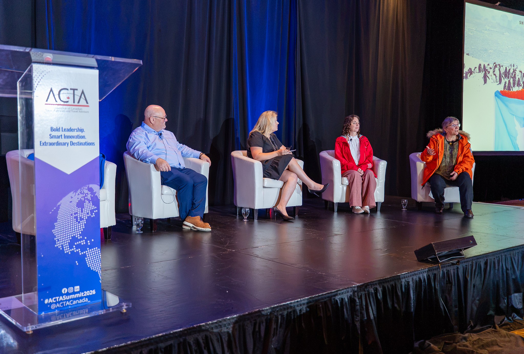 Sheila Gallant-Halloran wearing her National Geographic Antarctica parka on the ACTA Eastern Canada Summit main stage, speaking about expedition cruising.